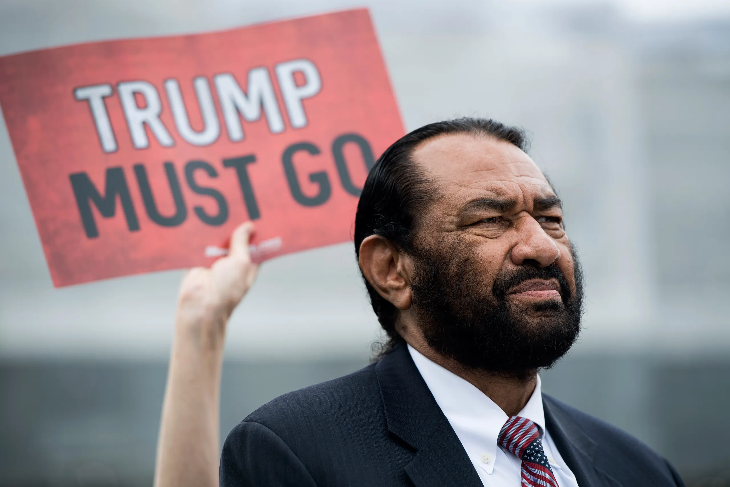 Rep. Al Green at the Capitol as a "Trump Must Go" sign is held behind him